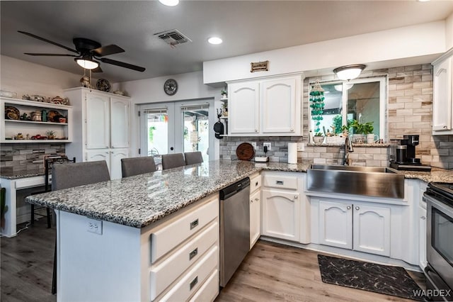 kitchen featuring appliances with stainless steel finishes, white cabinets, a sink, and a peninsula