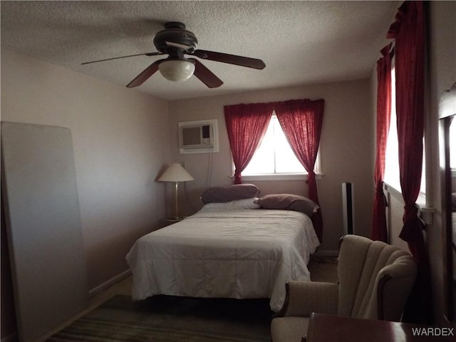 bedroom with a wall unit AC, a ceiling fan, and a textured ceiling