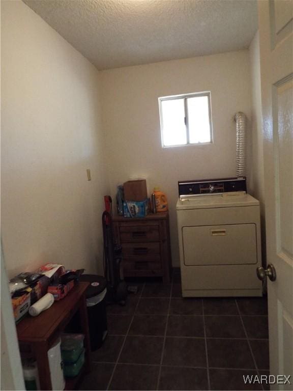 laundry area featuring washer / dryer, laundry area, a textured ceiling, and dark tile patterned flooring