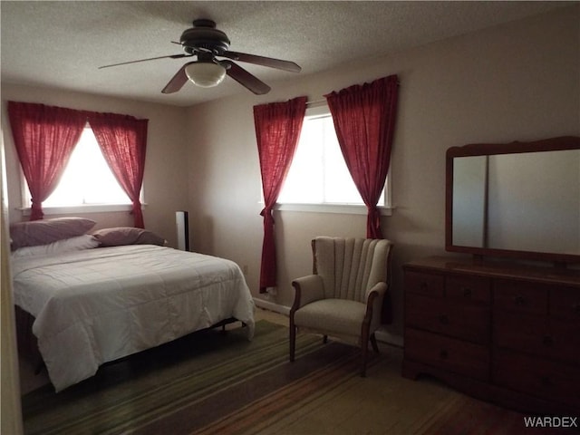 bedroom with multiple windows, dark wood finished floors, and a textured ceiling