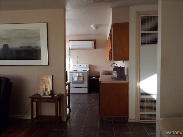 kitchen featuring a wall unit AC, light countertops, white electric range, brown cabinetry, and dark tile patterned flooring