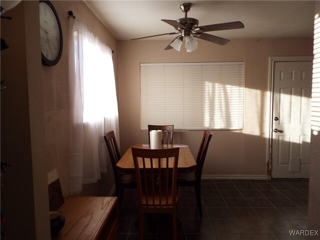 dining room with dark tile patterned flooring, a ceiling fan, and baseboards