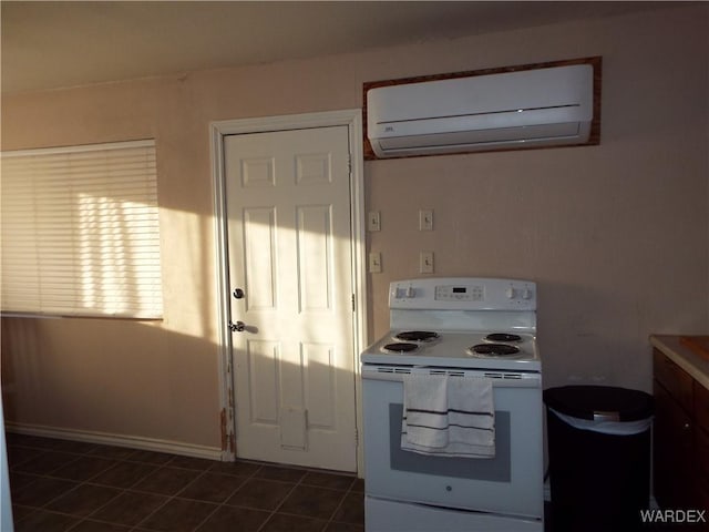 kitchen featuring dark tile patterned floors, white electric stove, baseboards, and a wall mounted air conditioner