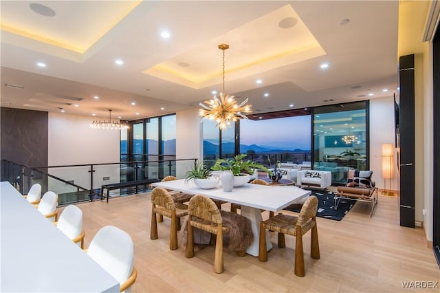 dining space with a chandelier, expansive windows, a raised ceiling, and recessed lighting