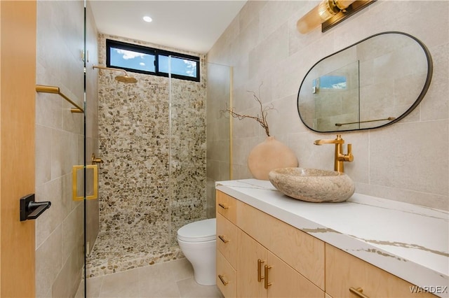 full bathroom featuring tile walls, toilet, a shower stall, vanity, and tile patterned flooring