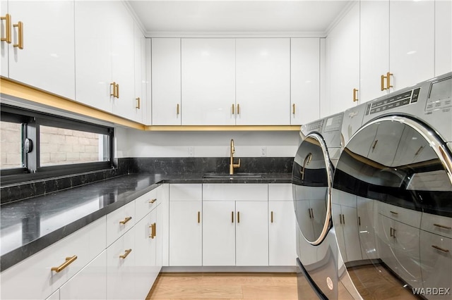 laundry room with light wood-type flooring, washing machine and dryer, cabinet space, and a sink