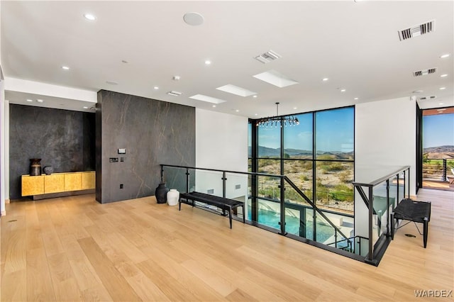 unfurnished room featuring a wall of windows, light wood-type flooring, and visible vents