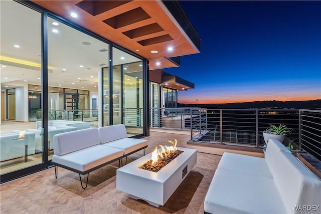 view of patio / terrace featuring a balcony and an outdoor living space with a fire pit