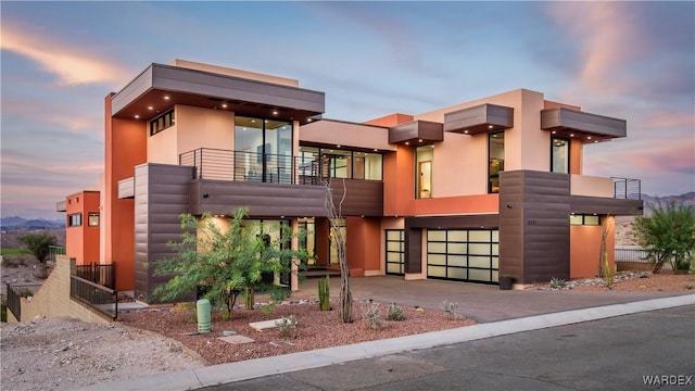 view of front of property featuring a garage, a balcony, and driveway