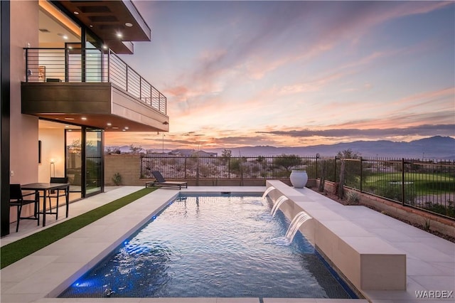 view of pool featuring a patio, fence, a mountain view, and a fenced in pool