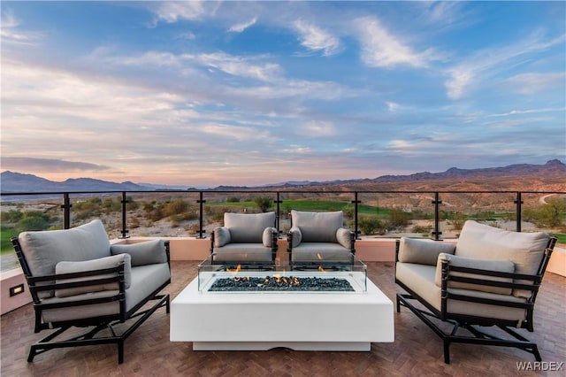 patio terrace at dusk with an outdoor living space with a fire pit and a mountain view