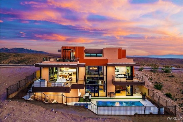 rear view of property with a fenced in pool, a patio area, a mountain view, a balcony, and fence