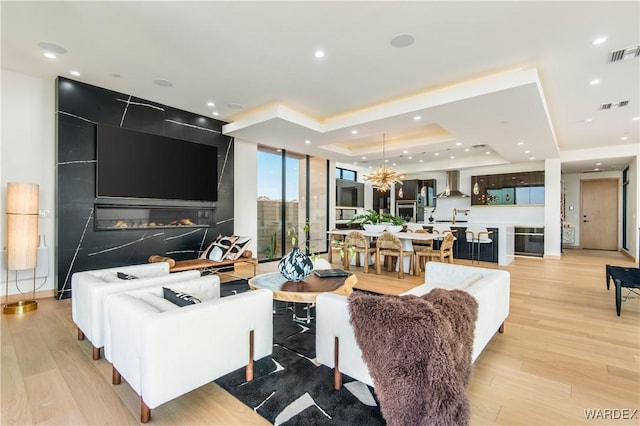 living area featuring light wood-type flooring, a raised ceiling, visible vents, and recessed lighting