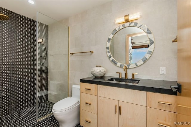 bathroom featuring a stall shower, tile walls, toilet, and vanity