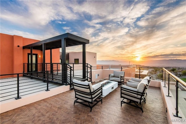 patio terrace at dusk with an outdoor living space with a fire pit and a balcony