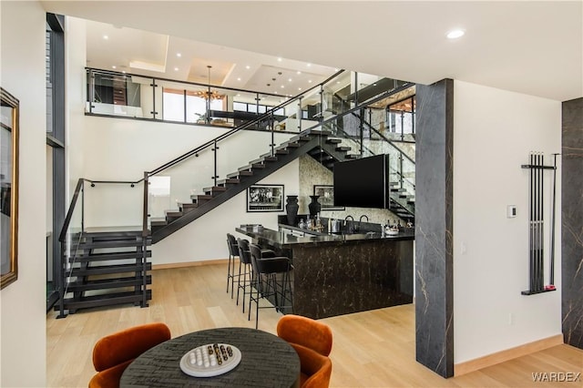 bar with wet bar, stairway, and wood finished floors