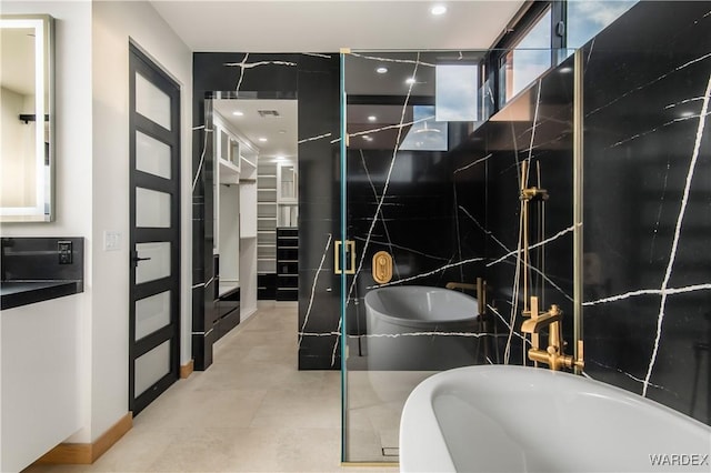 full bathroom featuring a soaking tub, tile patterned flooring, and tile walls