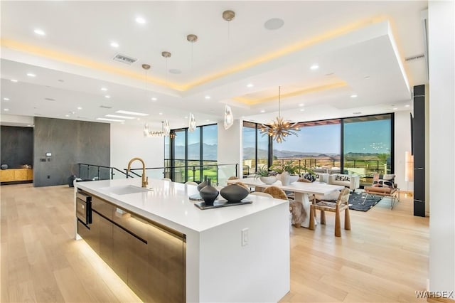 kitchen with a large island, open floor plan, a tray ceiling, light countertops, and pendant lighting