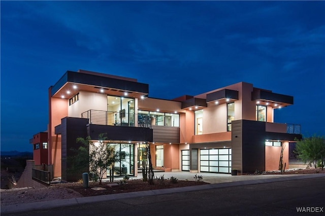 view of front facade featuring a garage, a balcony, driveway, and stucco siding