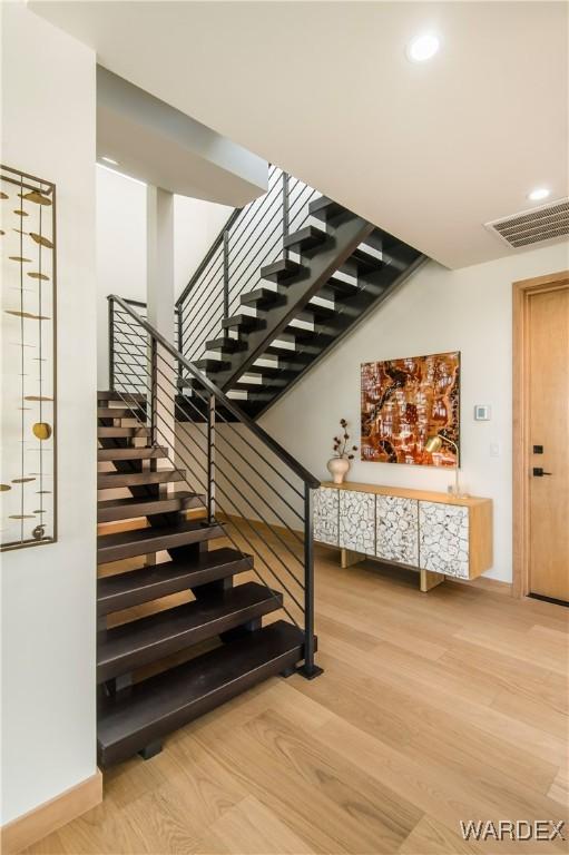 stairway featuring baseboards, visible vents, wood finished floors, and recessed lighting