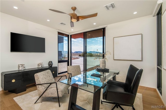 home office featuring light wood-style floors, floor to ceiling windows, and visible vents