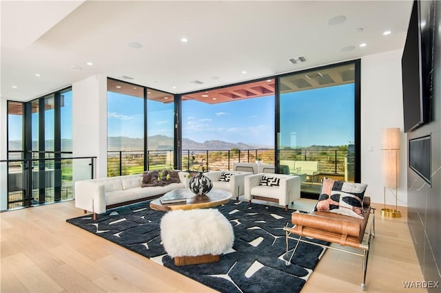 living room with light wood-style flooring, visible vents, and floor to ceiling windows