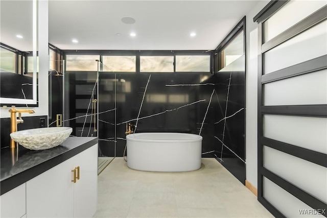 bathroom featuring tile patterned flooring, a freestanding tub, vanity, and recessed lighting