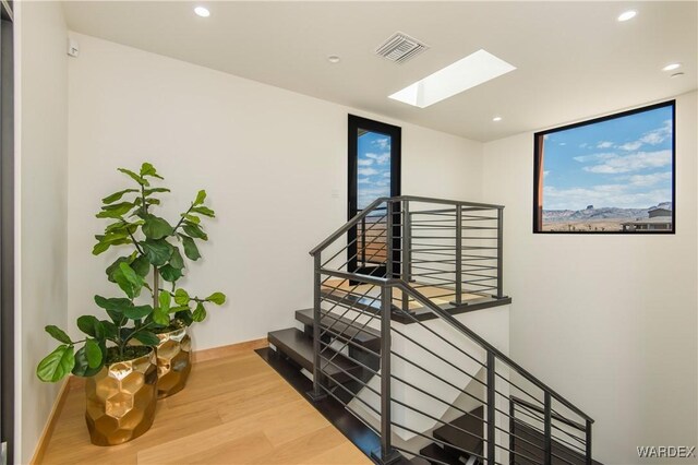 stairs with a skylight, visible vents, recessed lighting, and wood finished floors