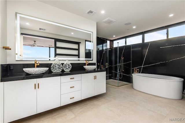 bathroom with double vanity, a soaking tub, visible vents, and a sink