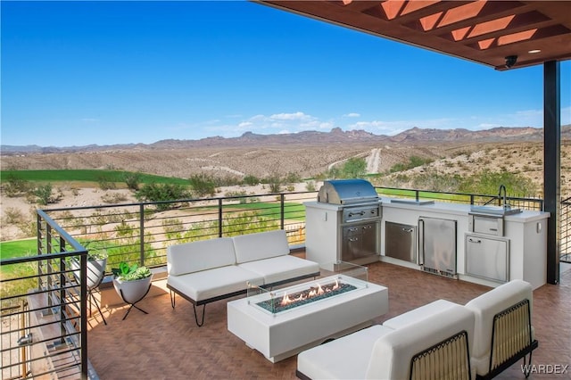 view of patio / terrace featuring an outdoor living space with a fire pit, an outdoor kitchen, a grill, and a mountain view