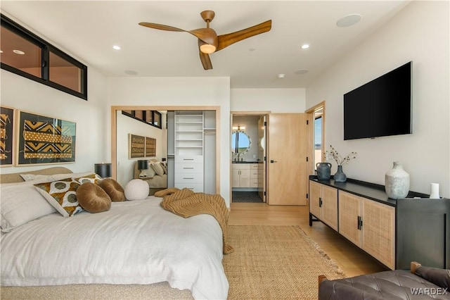 bedroom featuring a ceiling fan, ensuite bath, light wood-style flooring, and recessed lighting