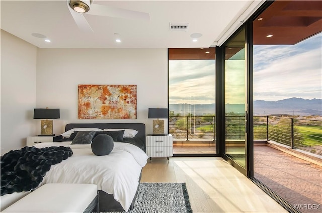 bedroom featuring visible vents, access to exterior, a wall of windows, light wood-style floors, and a mountain view