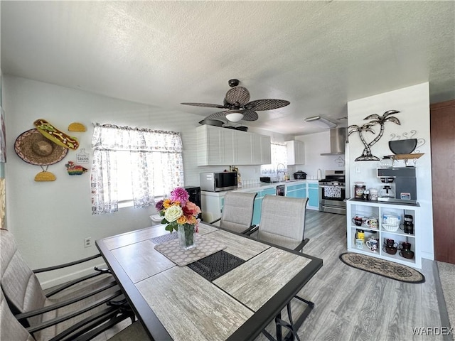 dining room with a textured ceiling, ceiling fan, and light wood-type flooring