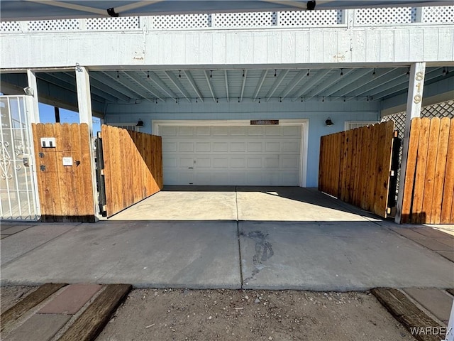 garage with a carport, a gate, fence, and driveway