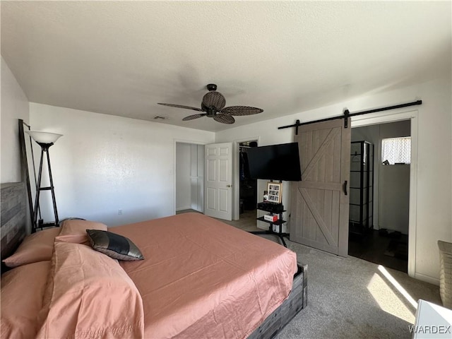 carpeted bedroom featuring a barn door, visible vents, and a ceiling fan