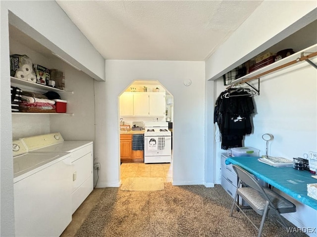 laundry room featuring a textured ceiling, light colored carpet, laundry area, baseboards, and washer and clothes dryer