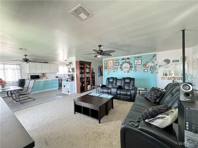 living room with ceiling fan, a textured ceiling, and visible vents