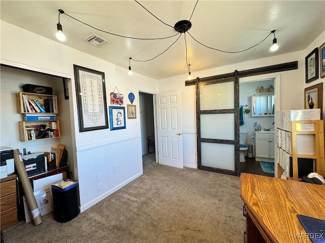 carpeted office space featuring visible vents, baseboards, and a barn door