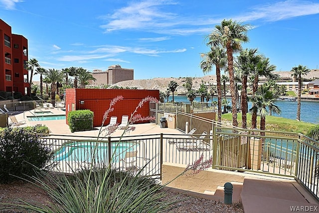 pool featuring a water view, fence, and a patio