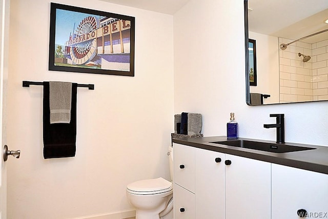 bathroom featuring toilet, baseboards, a shower, and vanity