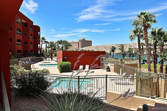 pool with a water view, a patio area, and fence