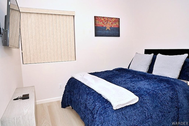 bedroom featuring light wood finished floors and baseboards