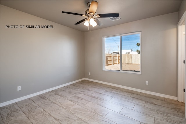 spare room with a ceiling fan and baseboards