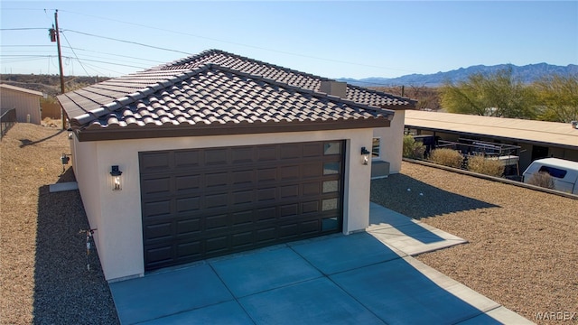 view of front of home with an outbuilding, a mountain view, a detached garage, a tile roof, and stucco siding