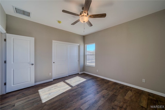 unfurnished bedroom featuring visible vents, dark wood finished floors, baseboards, and ceiling fan