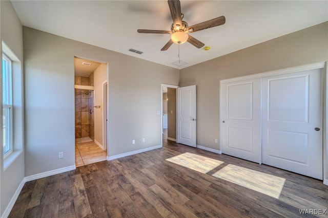 unfurnished bedroom with a closet, visible vents, ensuite bathroom, wood finished floors, and baseboards