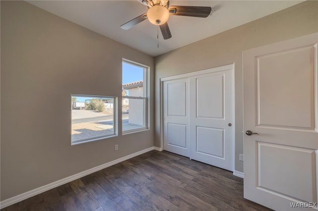 unfurnished bedroom with dark wood-type flooring, a closet, a ceiling fan, and baseboards