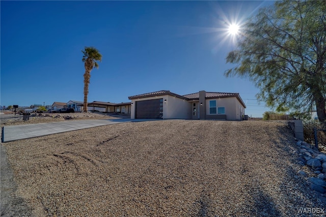 view of front of property featuring a garage, concrete driveway, a tile roof, and stucco siding