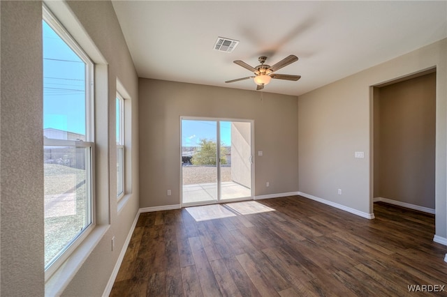 spare room featuring ceiling fan, dark wood finished floors, visible vents, and baseboards