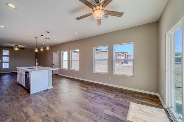 kitchen featuring a center island with sink, visible vents, dark wood-style flooring, light countertops, and pendant lighting